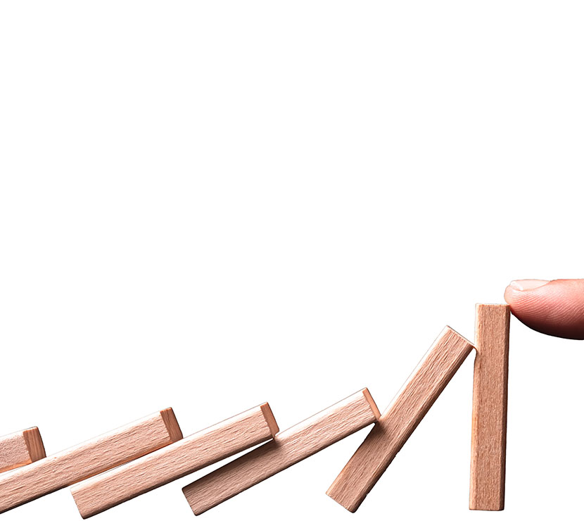 A finger stopping a row of small wooden blocks from falling