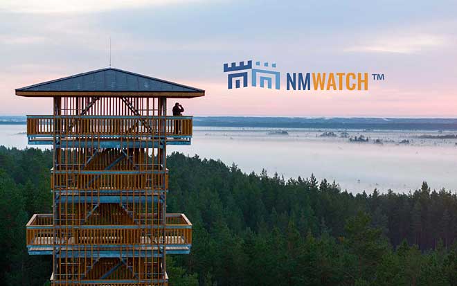 Man in wooden watchtower looking at mountain forest and water with binoculars