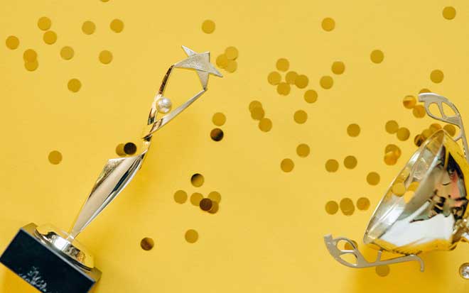 Awards lay on a yellow table with glitter.